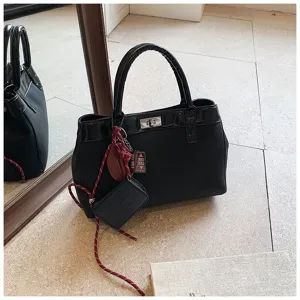 Black minimalist fashion tote handbag detail view, featuring premium fabric and chic lock.