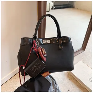 Detail shot of a black chic top-handle handbag with metal twist-lock and cute hanging pendants.