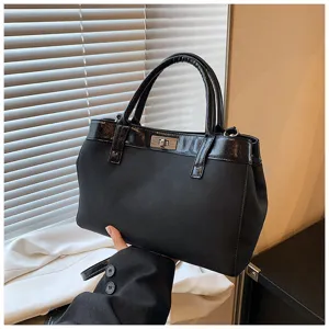 Detailed view of a black fashion top-handle handbag with chic metal lock and glossy trim.