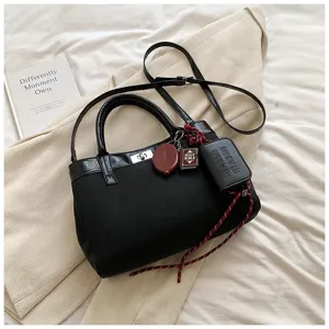 Black canvas patchwork crossbody shoulder bag for women with cute small book charms and handles.