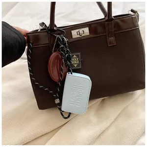 Detail view of niche fashion brown women handbag, autumn casual style with chic charms.