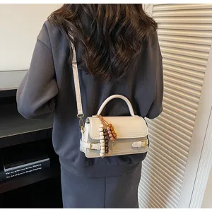 Detail shot of a stylish mini handbag with handle and beaded charm in modern elegant design.