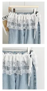 Detail view of women summer denim waistpiece overlay with white lace ruffles and ribbon.