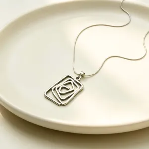 Collier pendentif spirale géométrique argenté détail, bijoux minimalistes tendance.
