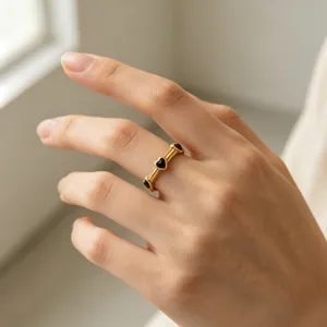 Primo piano ravvicinato e dettagliato dell'anello dorato con pietre nere a cuore.