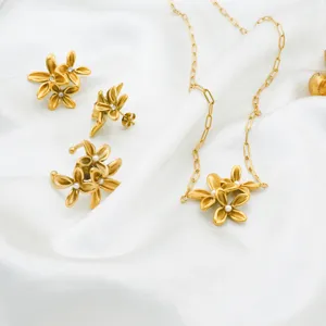 Detailaufnahme eines luxuriösen Goldblumen-Halsketten- und Ohrring-Sets auf weißer Seide.