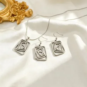 Vue détaillée d'un ensemble de bijoux collier et boucles d'oreilles spirale géométrique.