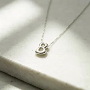 Close-up detail of the glossy puffed bubble pendant necklace on textured stone background.