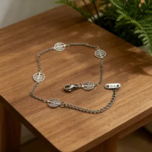 Silver chain bracelet detail view featuring delicate tree hollow round charms and lobster clasp.