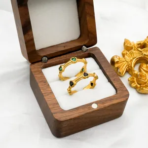 Primo piano di anelli dorati con zirconi a cuore in elegante scatola di legno.