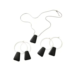 Minimalist geometric jewelry set with silver necklace and black pendant hoop earrings.