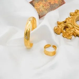 Detailed shot of gold stainless steel cuff bracelet and open ring set with diamond pattern.