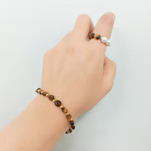 Detail shot of a vintage tiger eye beaded bracelet and pearl ring set, elegant jewelry piece.