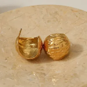 Detailed shot of textured gold C-shape dome earrings, elegant stainless steel jewelry.