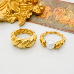 Detailopname van stijlvolle 18k vergulde draairingen met parelaccent en modern design.