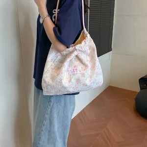 Detailed view of stylish floral shoulder tote bag with pink pattern and drawstring strap.