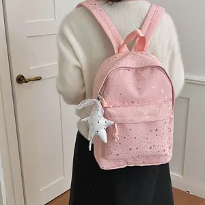 Vue detaillee de sac a dos rose etoile avec motif d'etoiles argentees et pendentif etoile blanche.