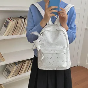 Vue détaillée du sac à dos blanc à motif d'étoiles avec joli pendentif en dentelle chic.