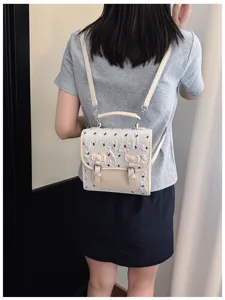 Detailed back view of a chic college style bow print mini backpack with double straps and buckle.