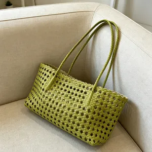 Green woven leather tote bag with grid cutout and scalloped edge for summer beach vacation.