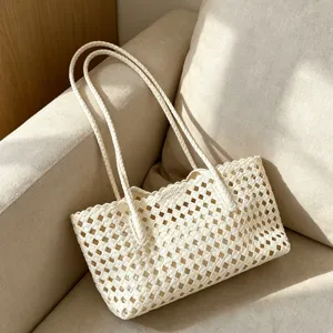 Close-up view of the chic off-white hollow-out woven beach tote bag with braided straps.