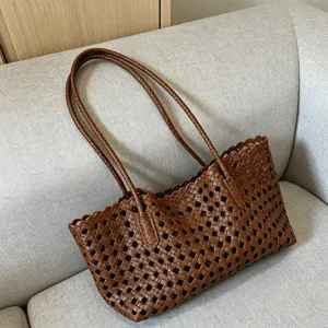 Close-up detail of the brown woven leather shoulder bag showing intricate hollow design.