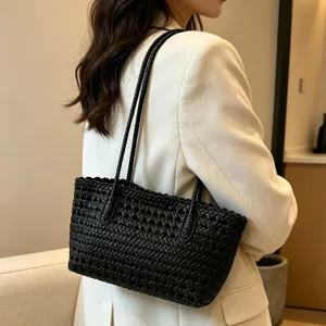 Detailed view of the black woven shoulder bag, elegant hollow design for beach summer.