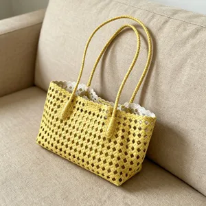 Detailed shot of a yellow woven hollow shoulder bag with white lace lining for summer beach.