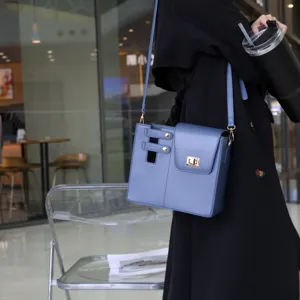 Stylish blue leather crossbody bag with metal lock and unique strap design for women daily use.