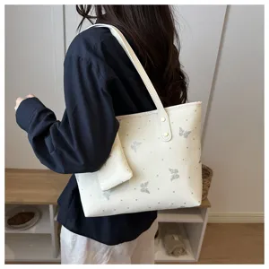 Close up view of stylish white shoulder tote bag featuring glitter butterfly prints and pouch.