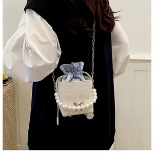 Stylish small bucket bag with pearl handle, chic bow accent and chain strap for women.