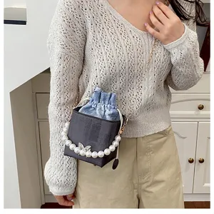 Small pearl chain bucket bag detail shot showcasing delicate denim drawstring and elegant design.
