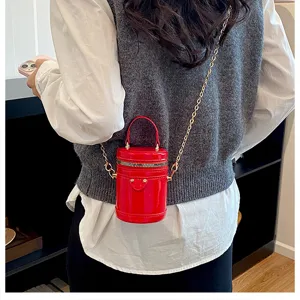 Vue de détail d'un mini sac à bandoulière cylindrique en cuir verni rouge avec chaîne.