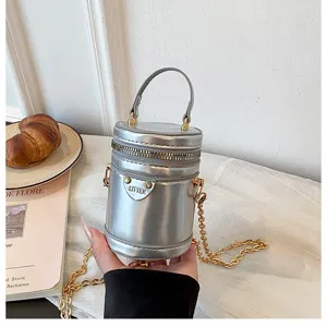 Mini sac bandoulière cylindrique métallisé argenté avec chaîne dorée, chic et compact.
