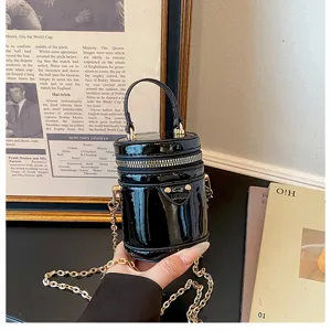 Petit sac bandoulière cylindrique en cuir verni noir avec chaîne dorée, élégant sac pour enfants.