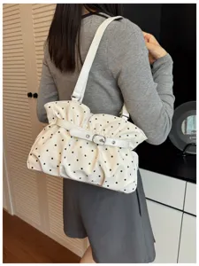 Vista dettagliata della borsa a spalla bianca a pois neri con fibbia elegante.