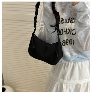 Black nylon underarm bag with pleated strap, minimalist crescent shoulder bag for women detail view.