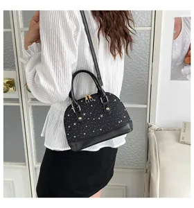 Vue détaillée du sac à main noir élégant avec motif d'étoiles et bandoulière réglable.