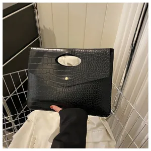 Vista dettagliata della borsa pochette nera con stampa coccodrillo, manico e bottone a pressione.