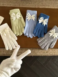 Women's knitted gloves featuring delicate lace bow and pearl details, warm winter detail shot.