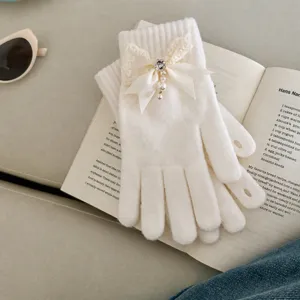 White knitted glove detail close up, featuring pearl lace bow, elegant winter warm accessory.
