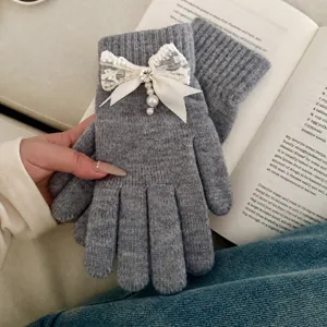 Detail shot of women's grey knitted gloves featuring elegant lace pearl bow for autumn winter.
