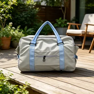 Vista dettagliata di una borsa da viaggio grigia con manici blu su una terrazza in legno.