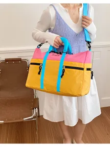 Close-up detail of color-blocked travel bag with pink, yellow and blue straps, durable.