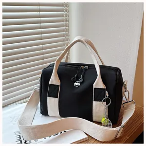 Schwarze Canvas-Fasstasche mit weißen dicken Trägern und einem süßen Tennis-Schlüsselanhänger.