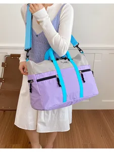 Close-up detail of the colorful travel duffel bag showing zipper pockets and sturdy straps.