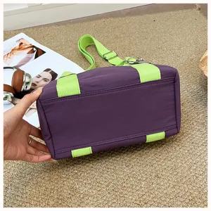 Detailansicht der lila Handtasche mit hellgrünen Trägern aus robustem Oxford-Stoff.