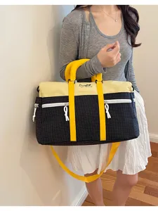 Detail view of a color block travel duffel bag with stylish yellow handles and grid pattern.