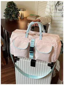 Borsone da viaggio rosa con tasche multiple e manici azzurri, ideale per sport e fine settimana.