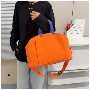 Vista dettagliata della grande borsa da viaggio con manici blu e corpo in tessuto arancione.